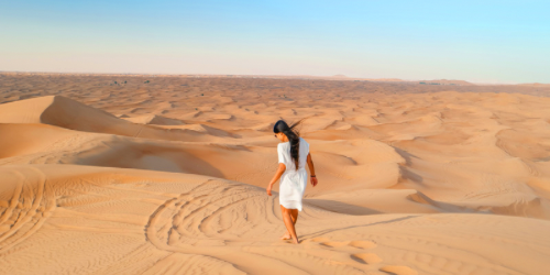 Image of an expat woman walking barefoot in the Dubai desert
